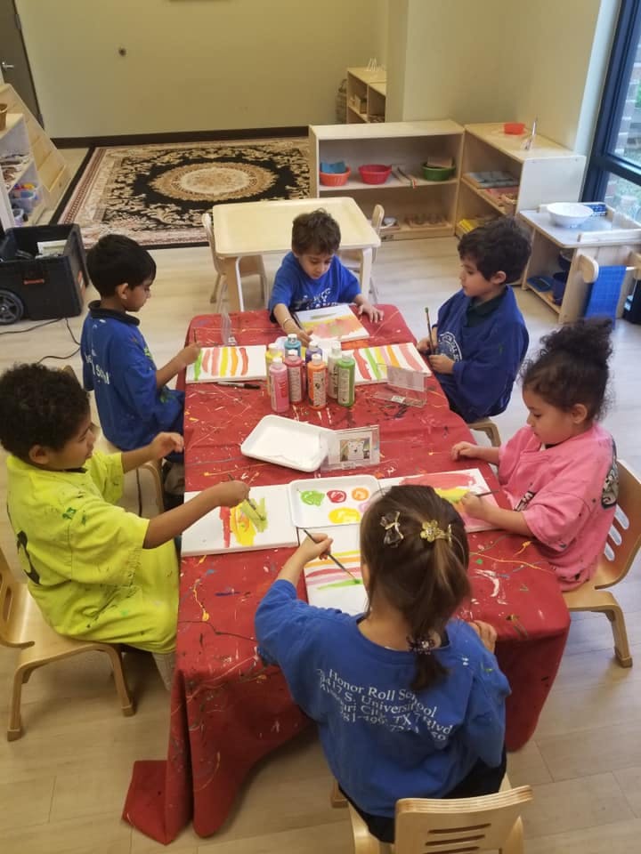 Children painting at a table in a classroom