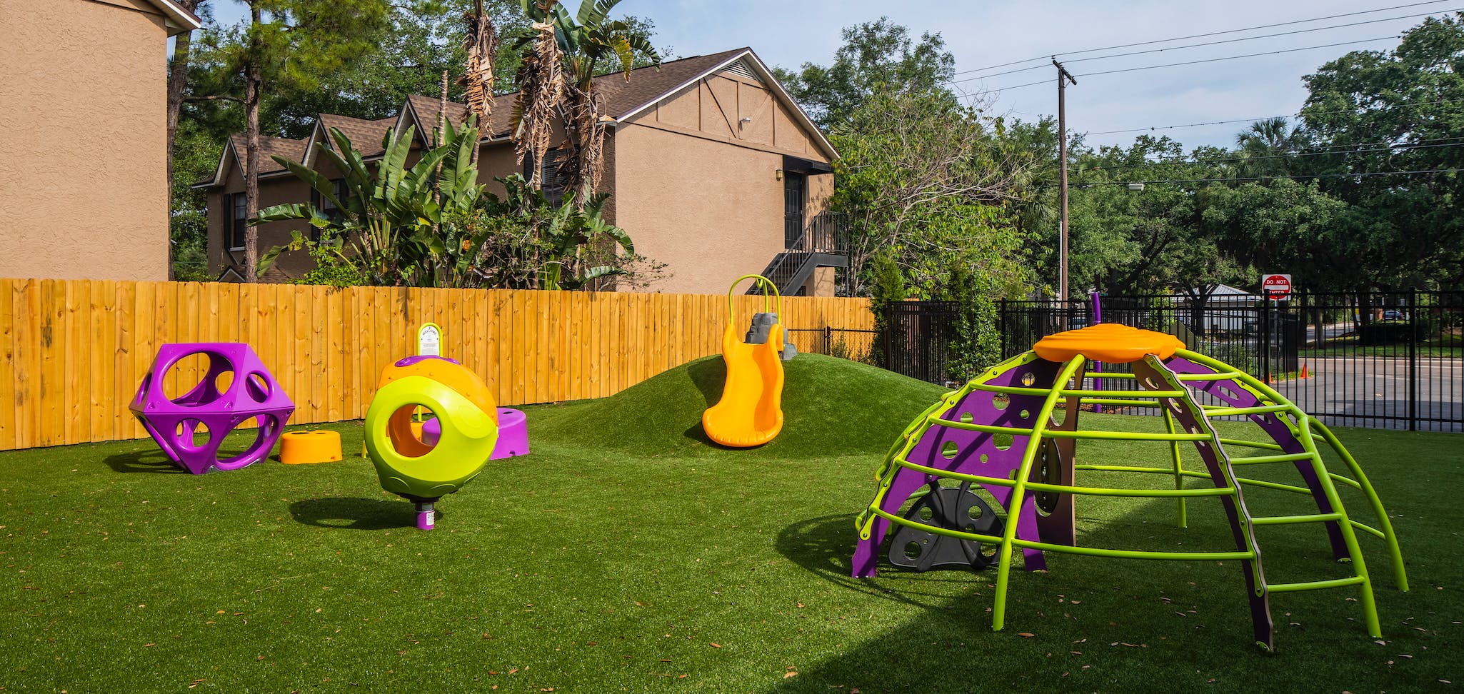 Playground with various purple, orange, and green play equipment on artificial turf