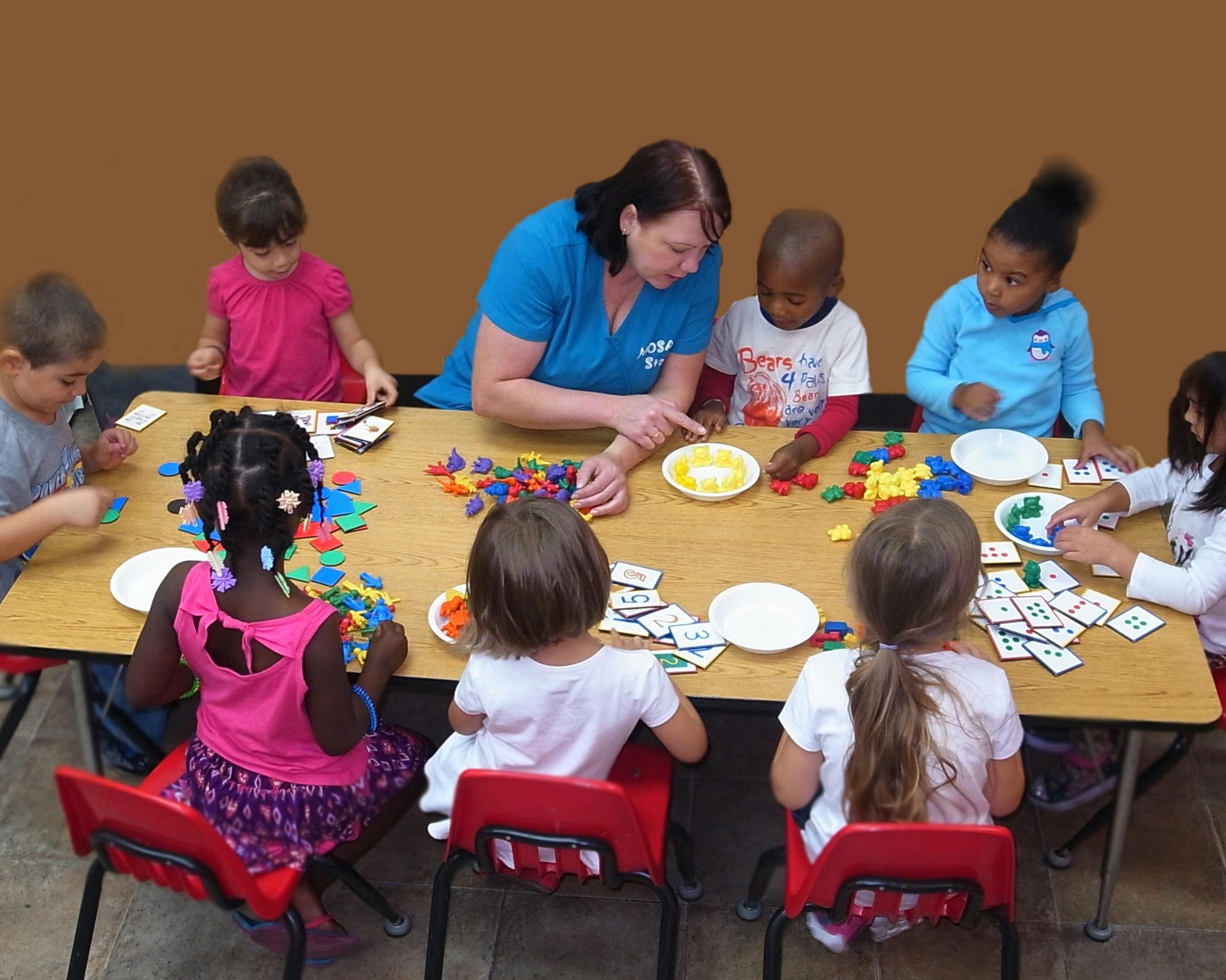 Adult and children at a table with toys and cards