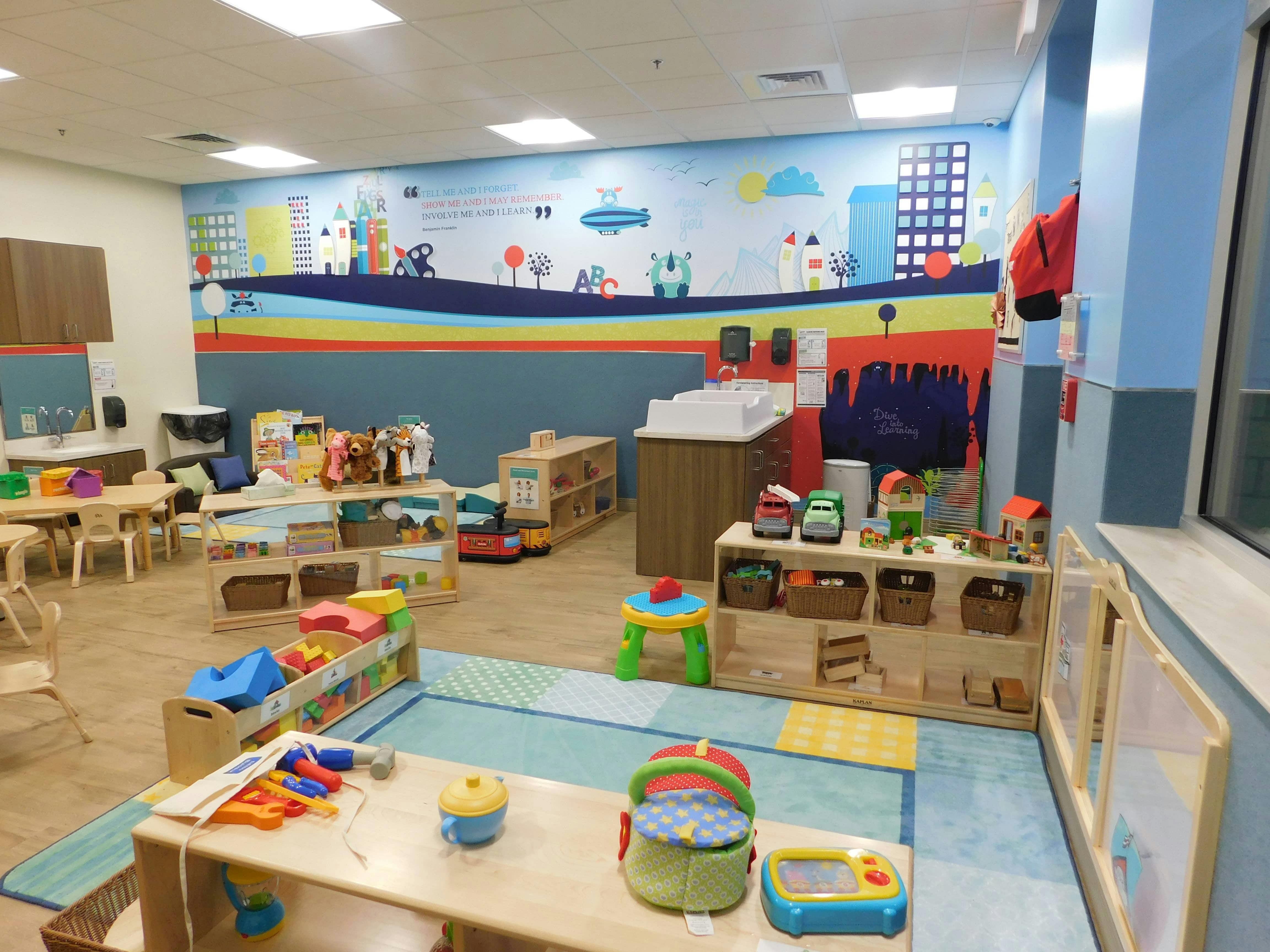 Playroom with colorful wall mural and various toys and furniture
