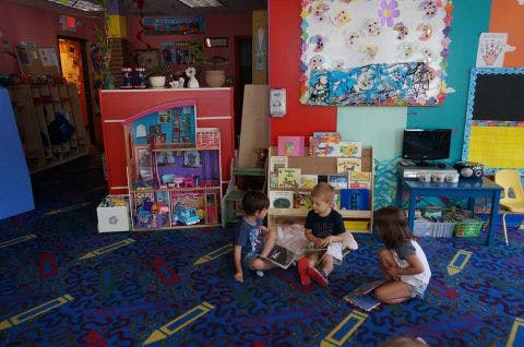 Three children sitting on a carpeted floor in a classroom