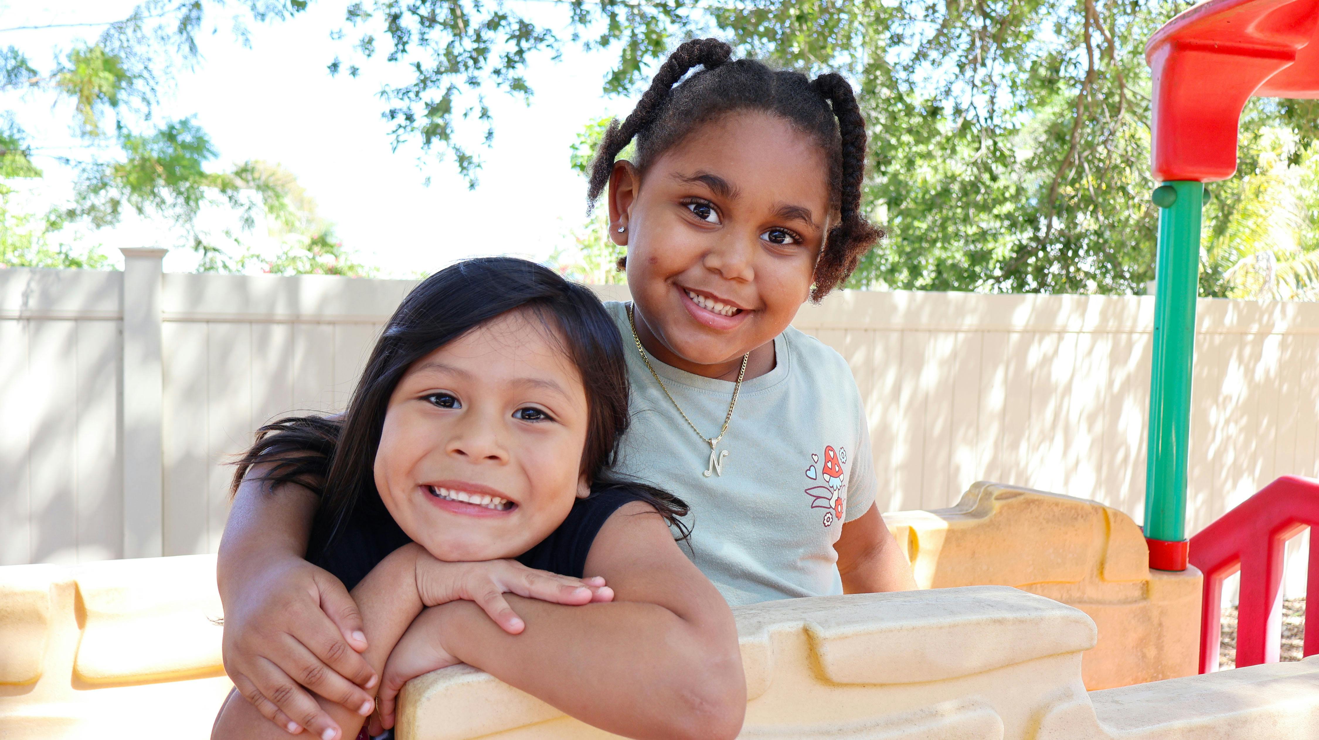 Two children posing together on a playground structure