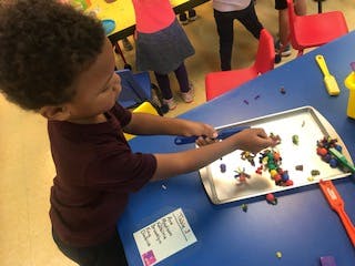 Child playing with colorful clay on a tray at a blue table