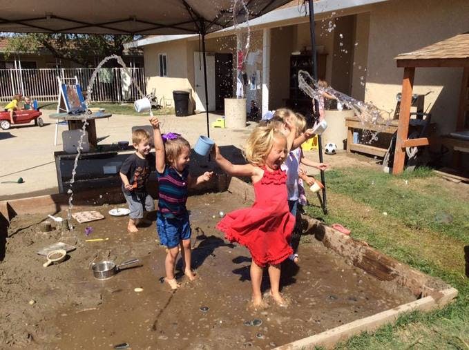 Children playing in a muddy sandbox with water