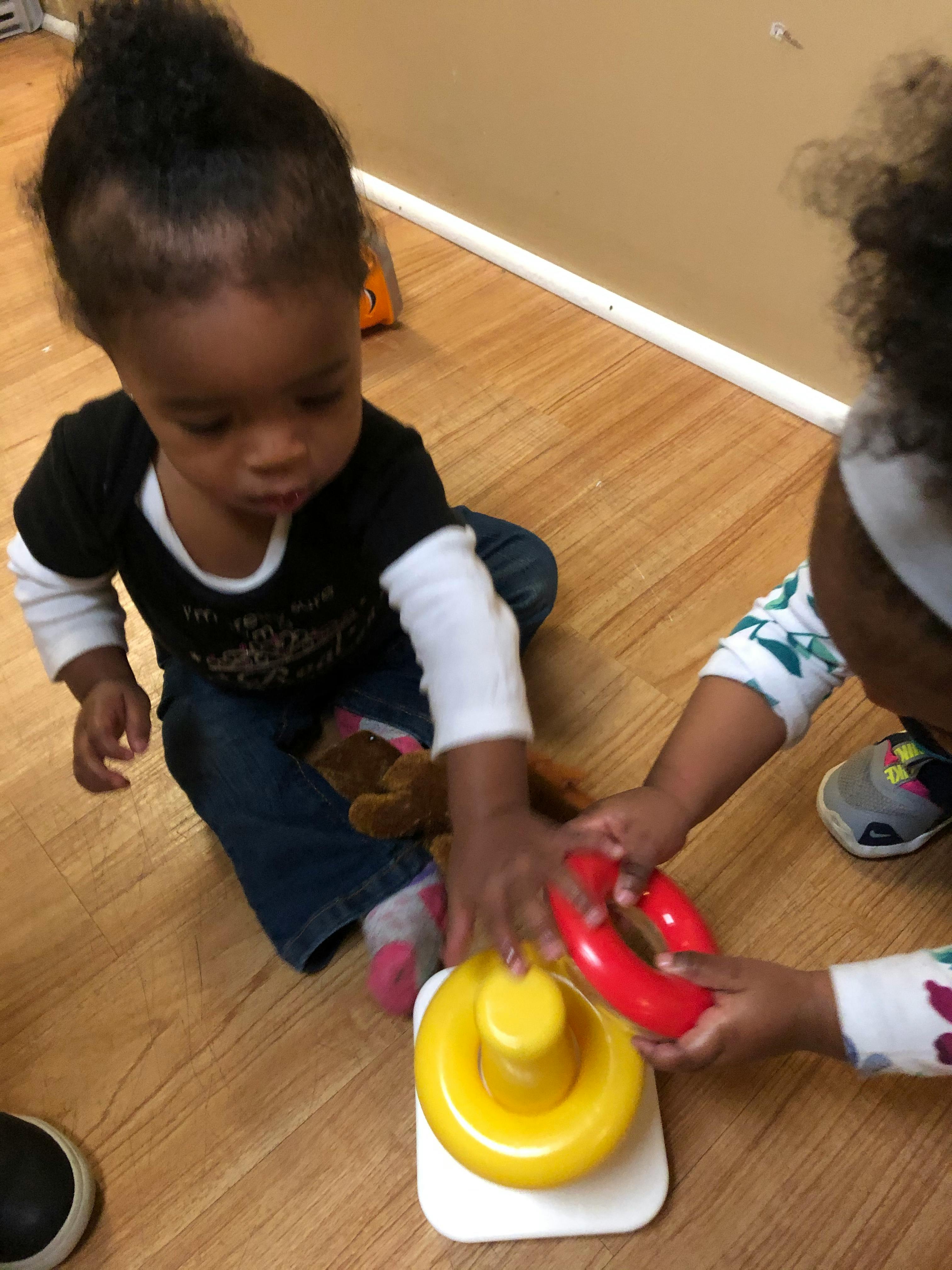 Two children playing with a ring stacker toy