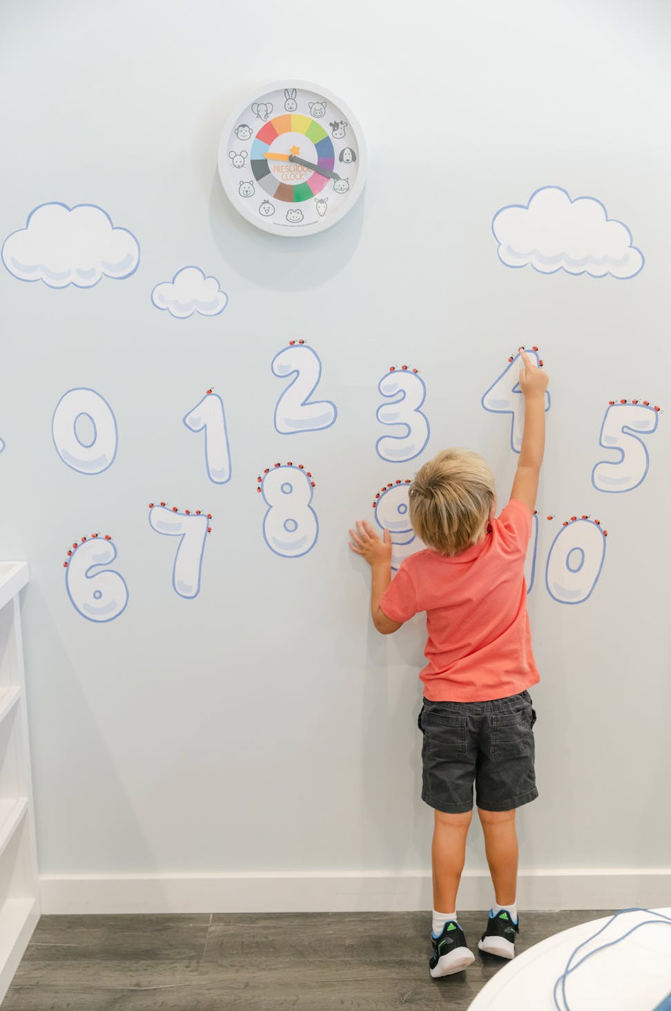 Child reaching up to touch numbers on a wall
