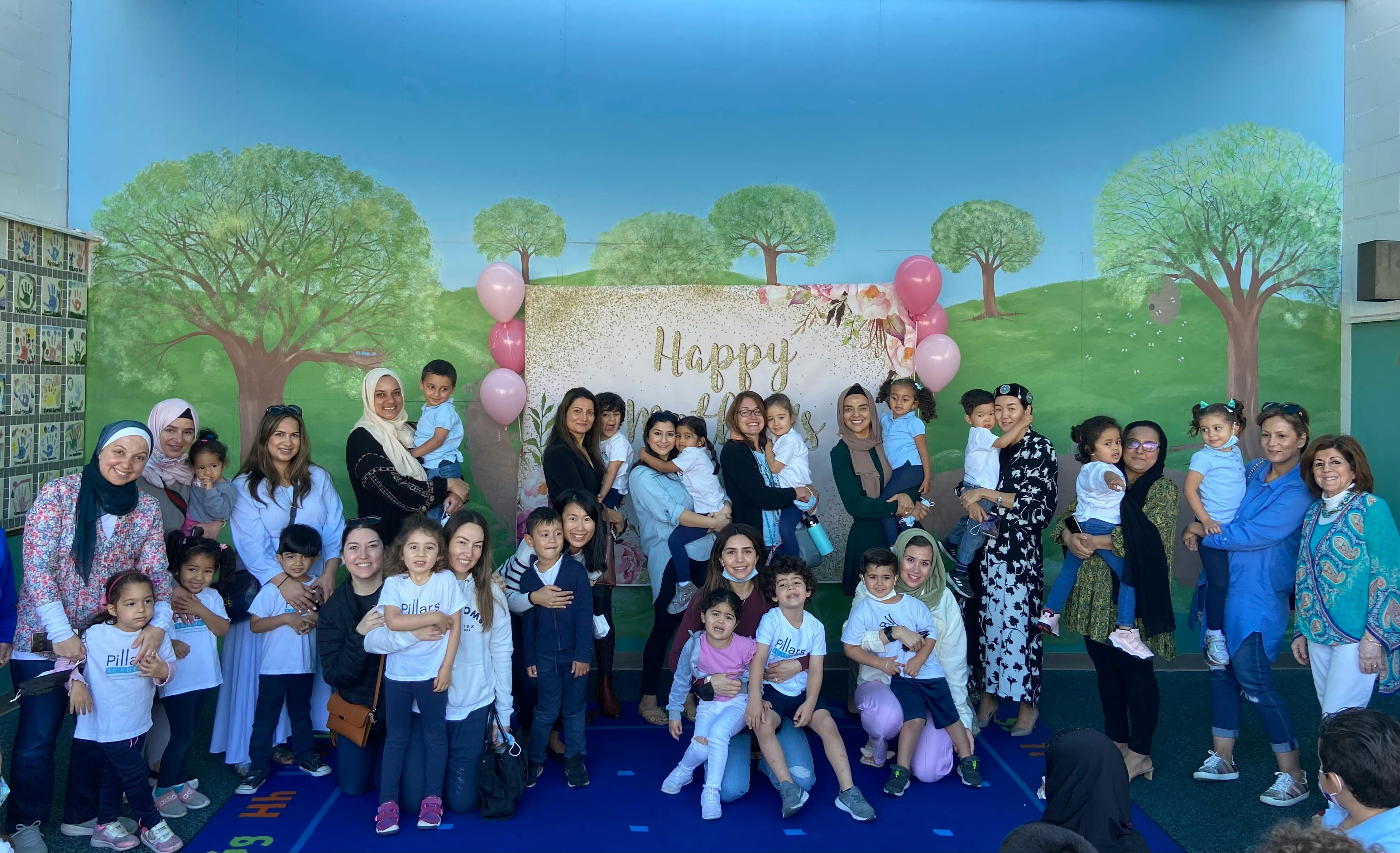 Group of adults and children posing in front of a "Happy" banner