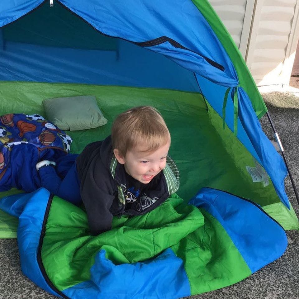 Child lying in a blue and green tent