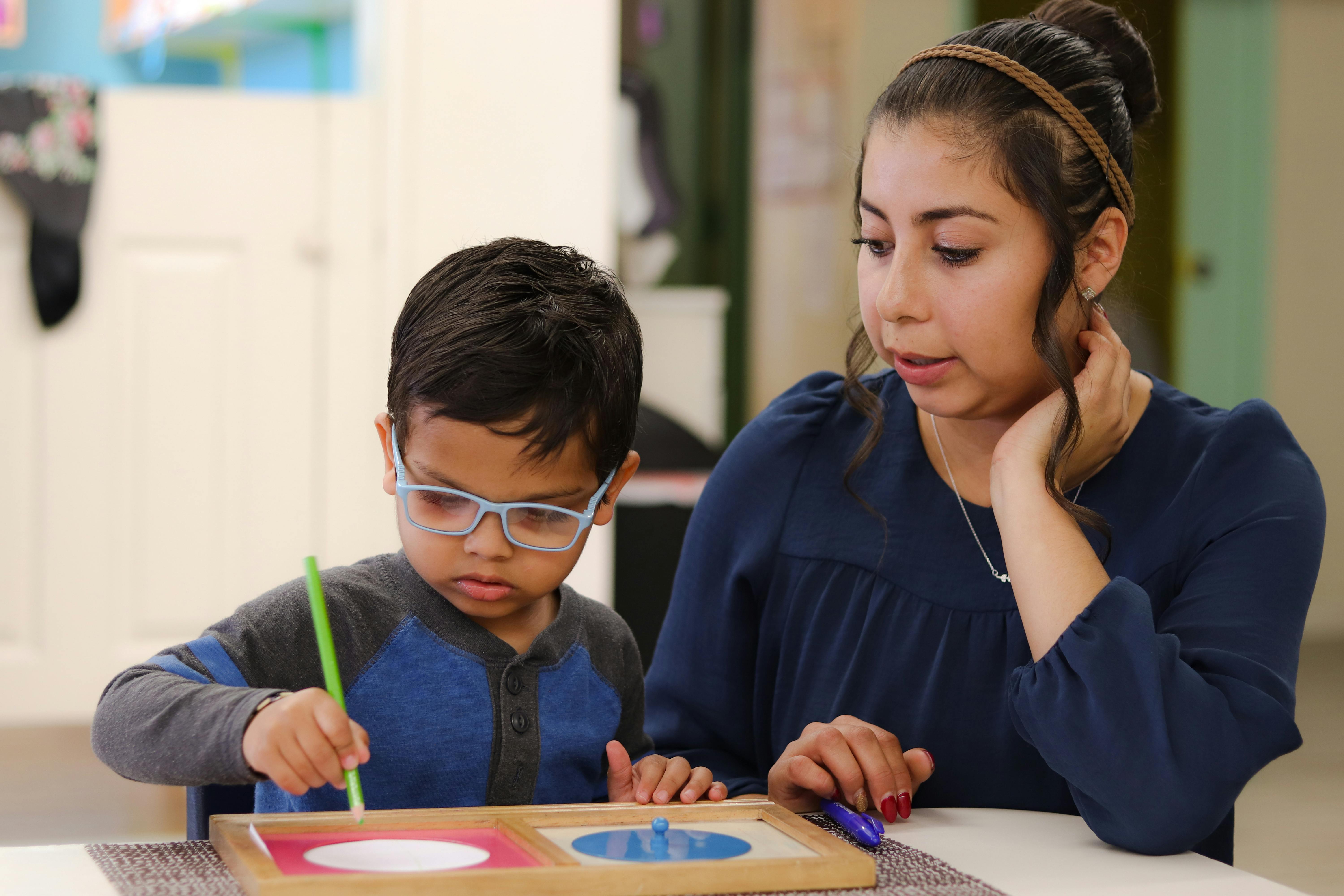Adult and child working on a shape puzzle in a classroom