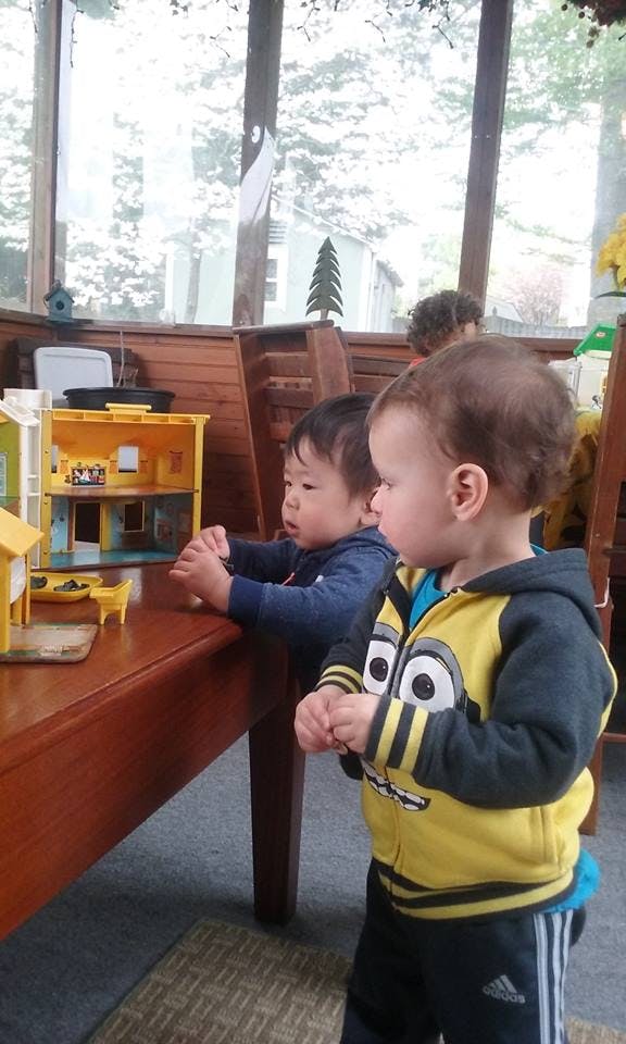 Two children playing with a dollhouse on a table