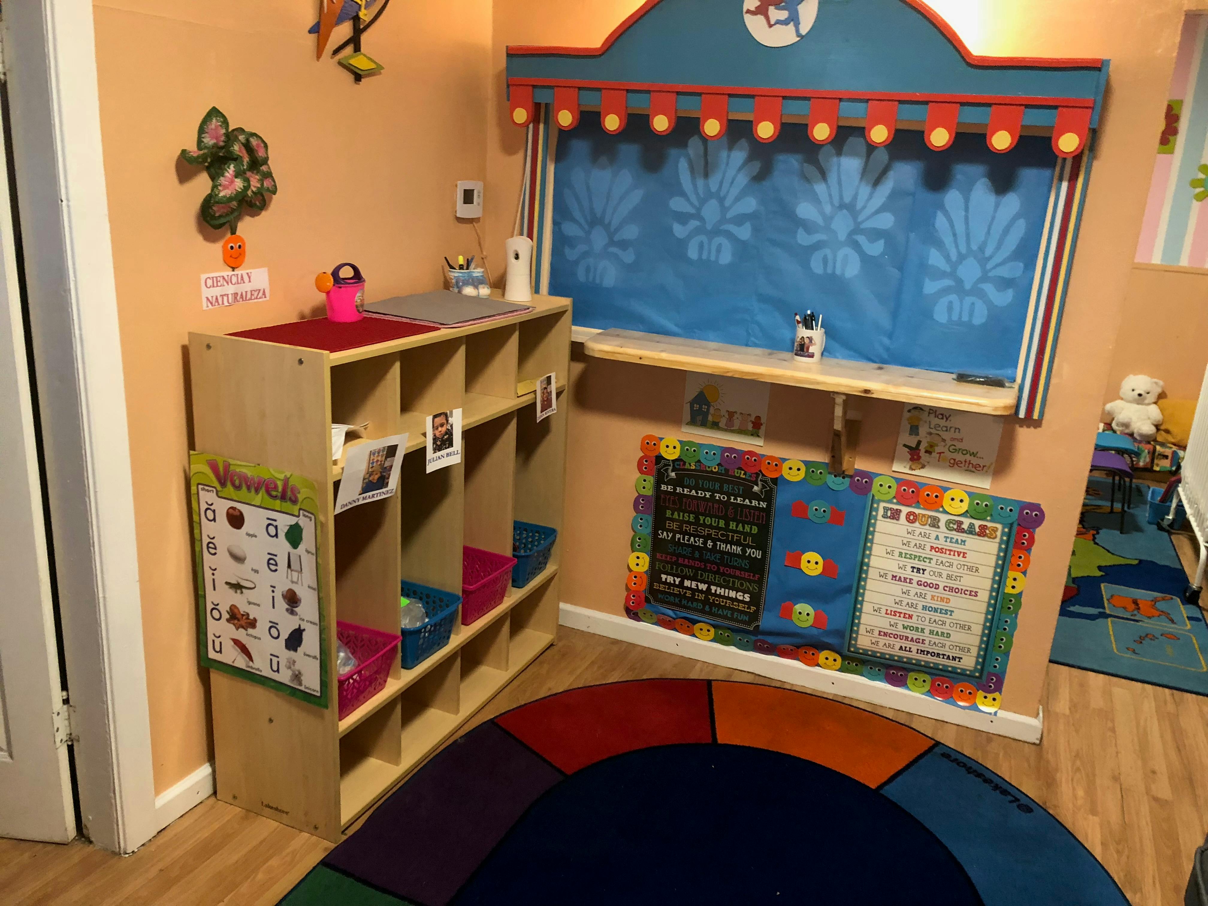 Classroom with cubbies, a puppet stage, and a colorful rug