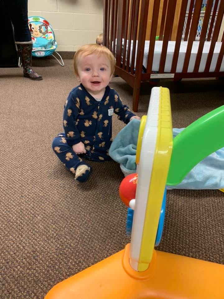 Child sitting on floor next to a crib