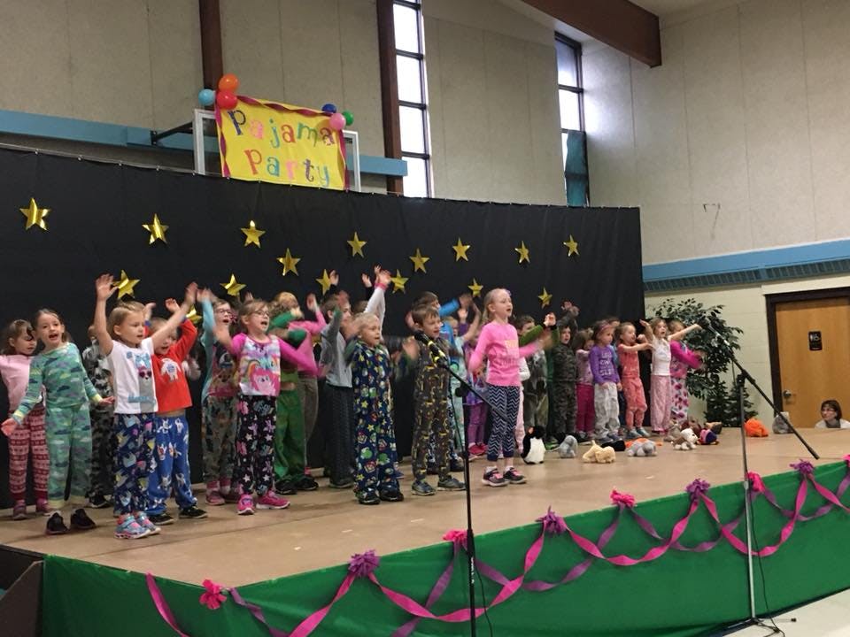 Children in pajamas on a stage with a "Pajama Party" sign