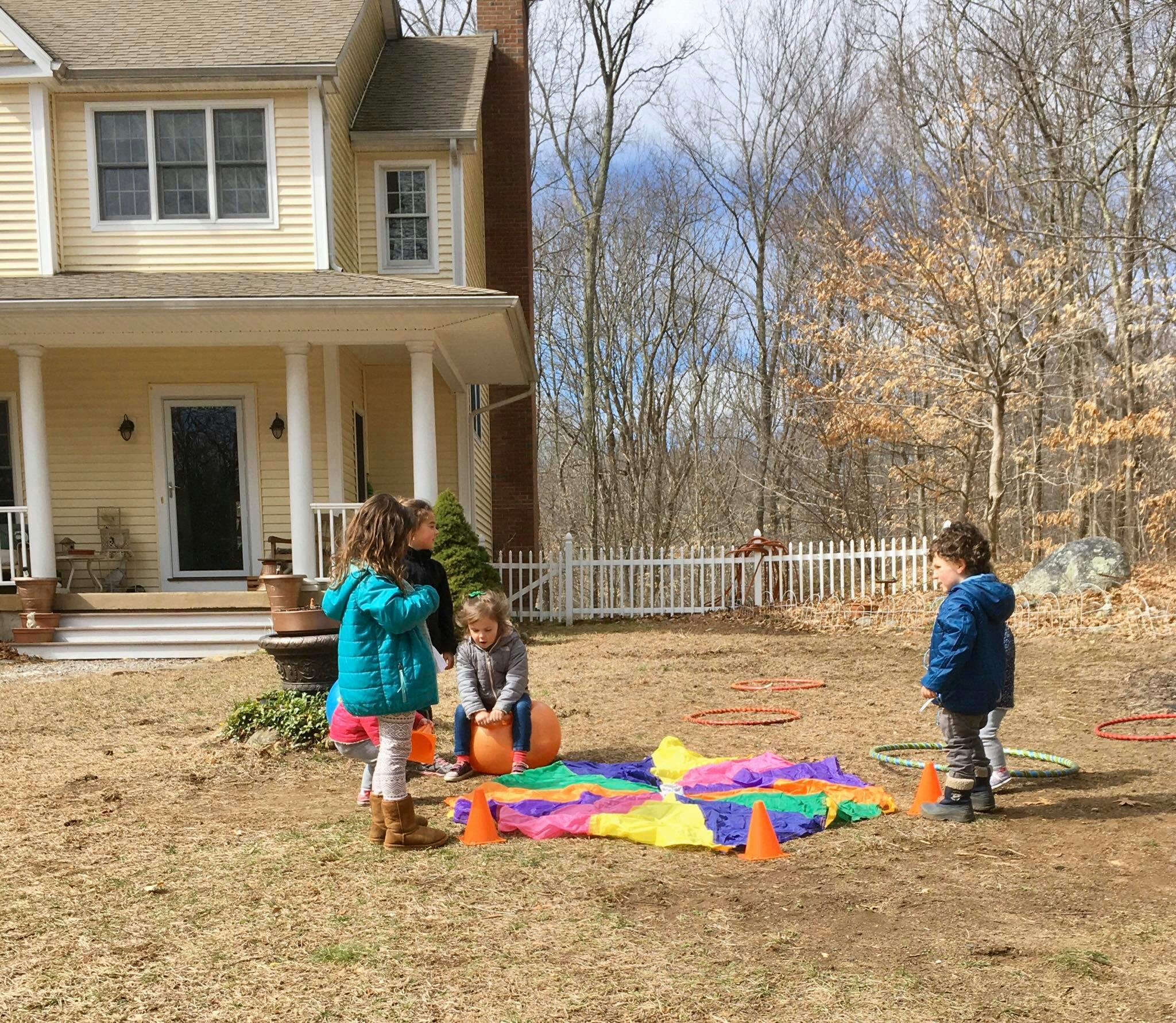Children playing outdoors with a colorful mat and cones