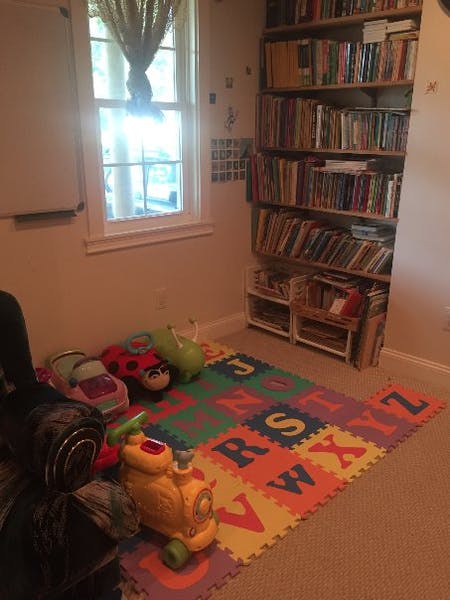 Playroom with alphabet mat, toys, window, and bookshelf