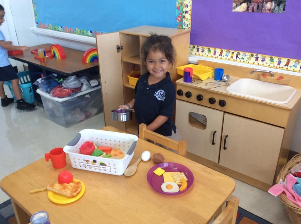 Child playing with toy kitchen and food