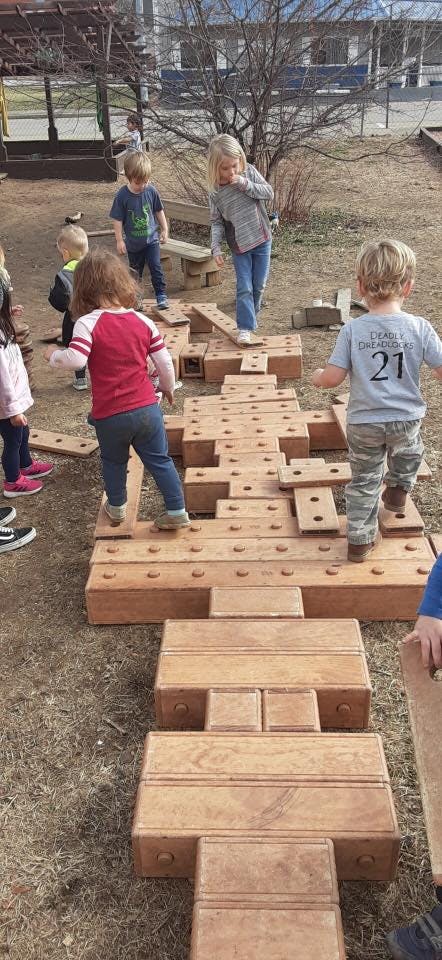 Children playing on wooden blocks outdoors