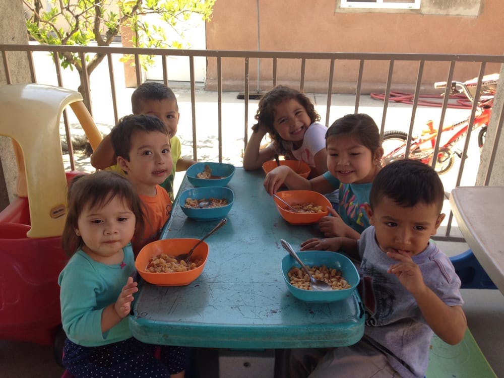 Six children sitting around a table with bowls of food