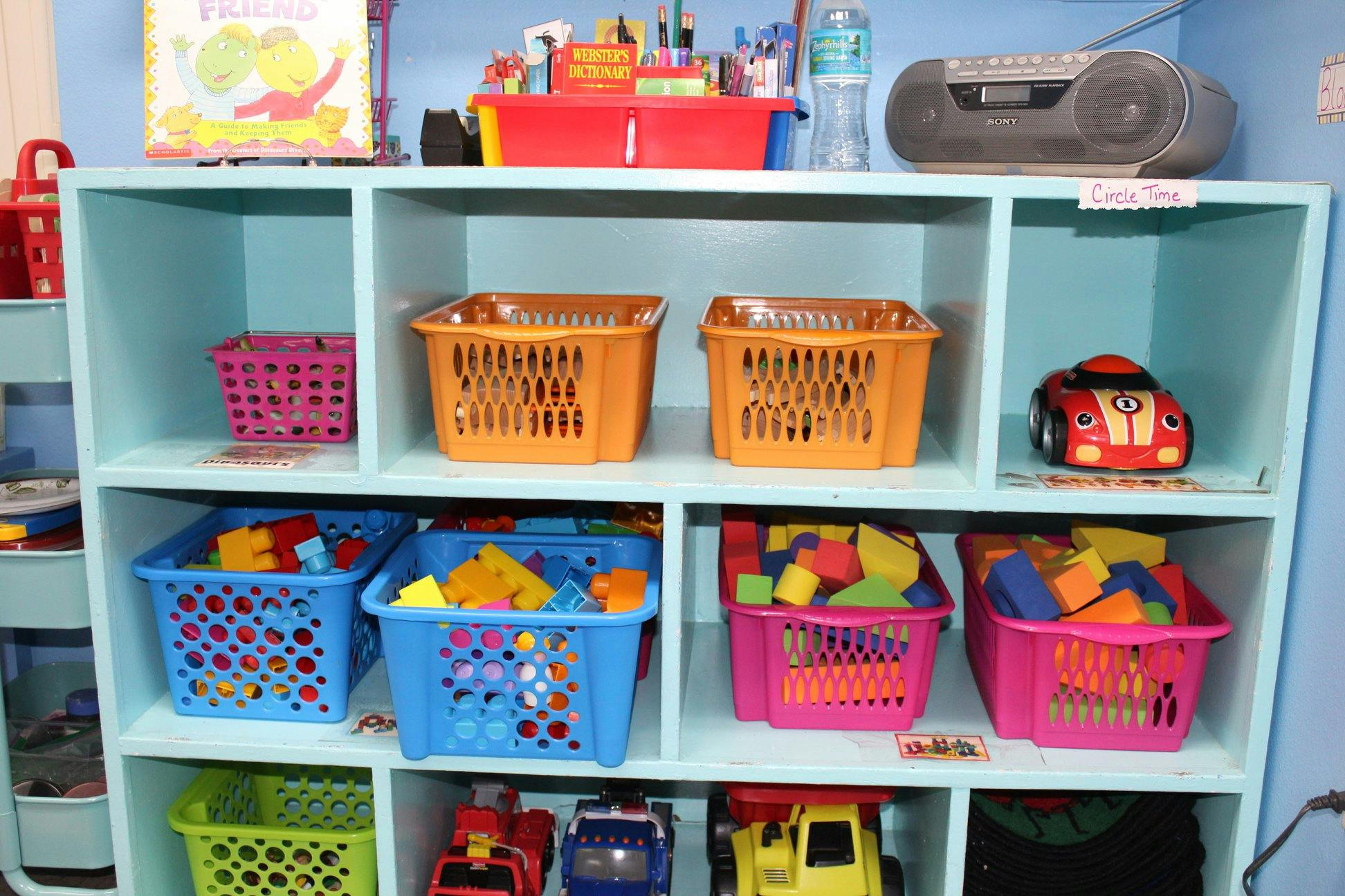 Shelves with colorful baskets of toys and a red toy car