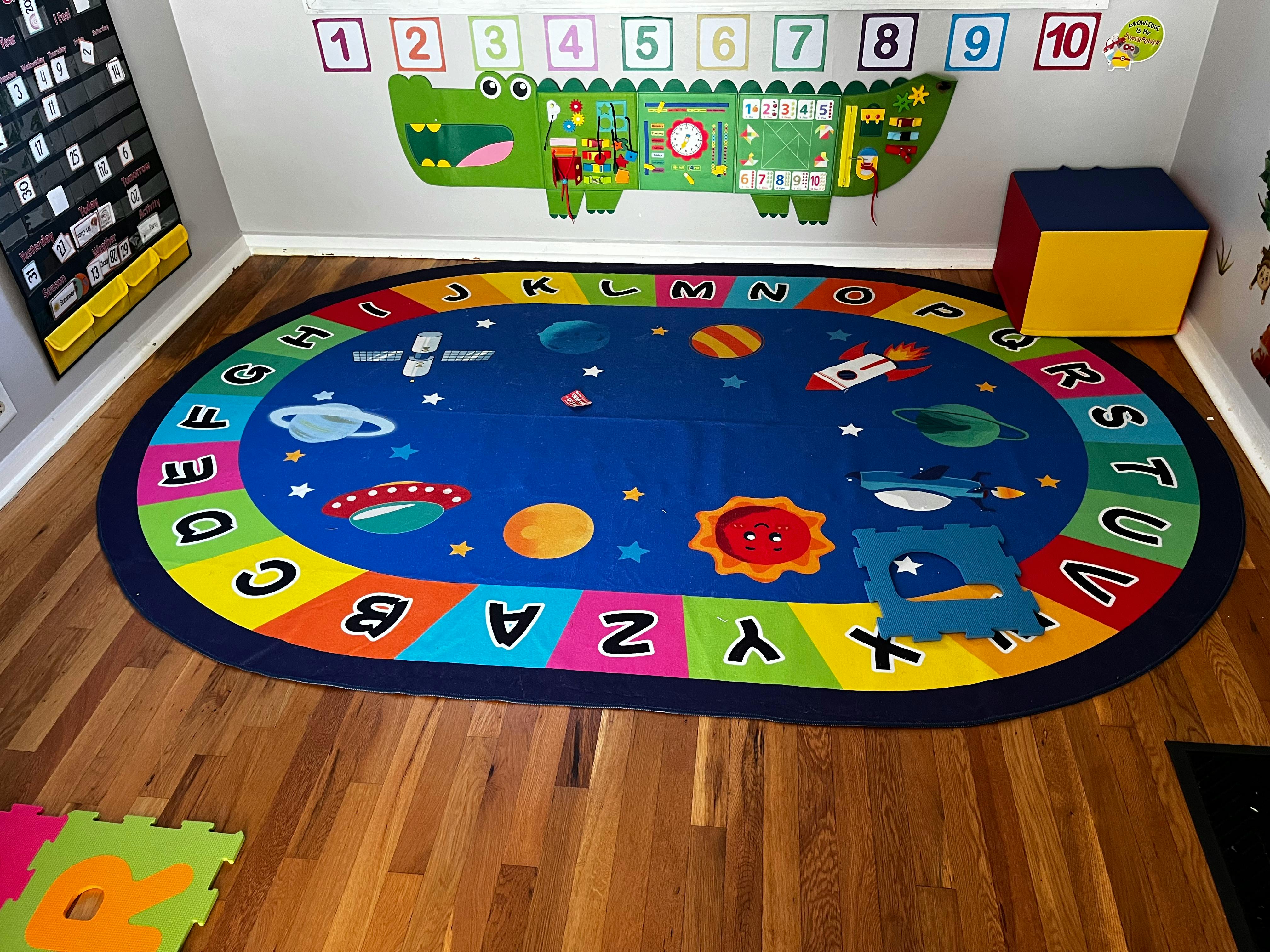 Oval blue rug with planets and alphabet border on a wooden floor