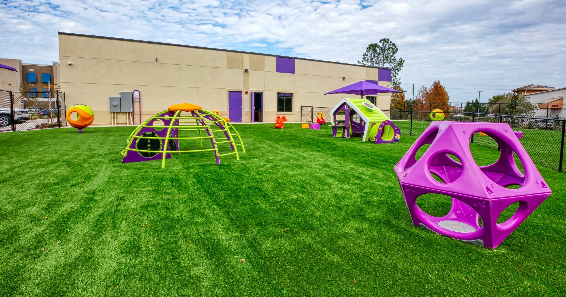 Playground with purple and green climbing structures on artificial turf
