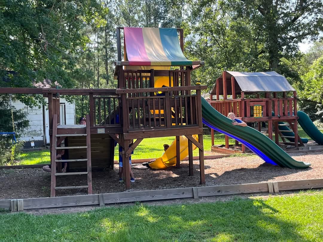 Child on a green slide at a wooden playground