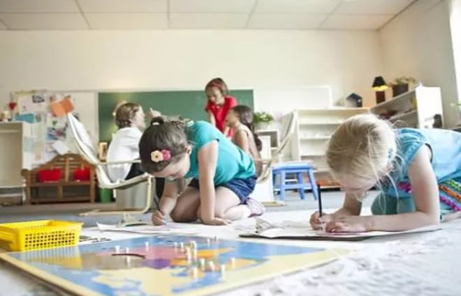 Children drawing on the floor in a classroom