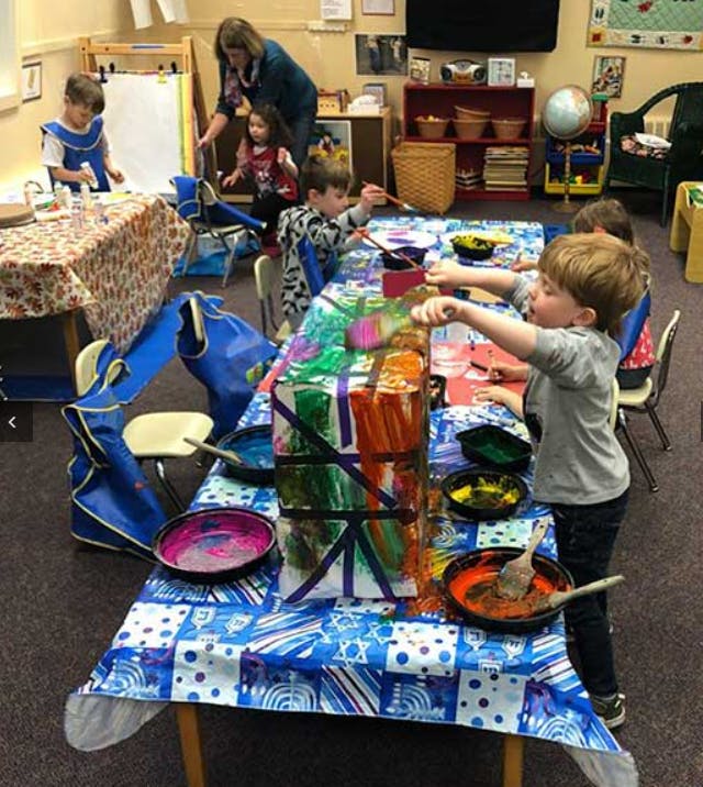 Children painting a large box in a classroom