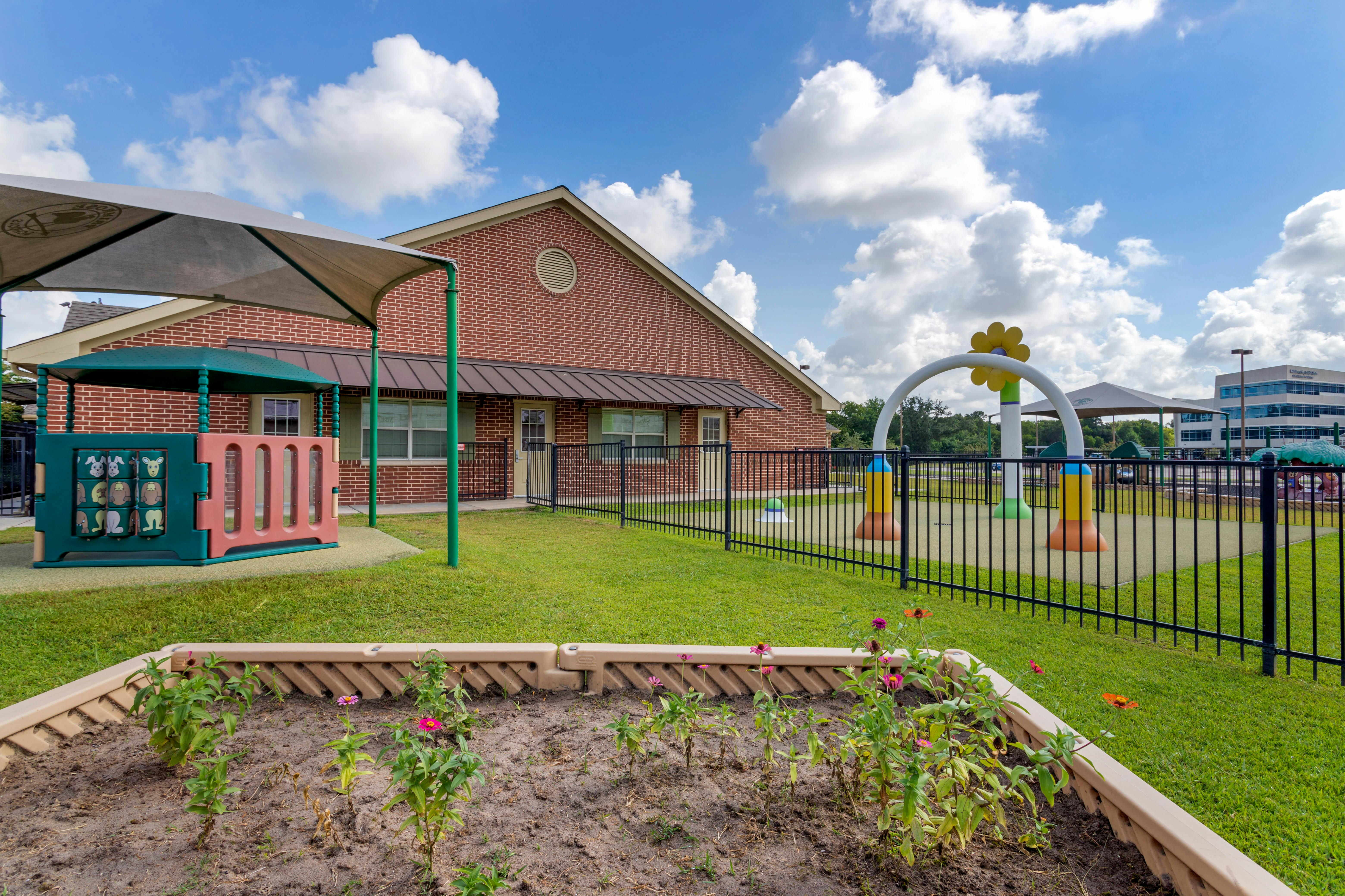 Outdoor children's playground with brick building, fences, and flowerbed