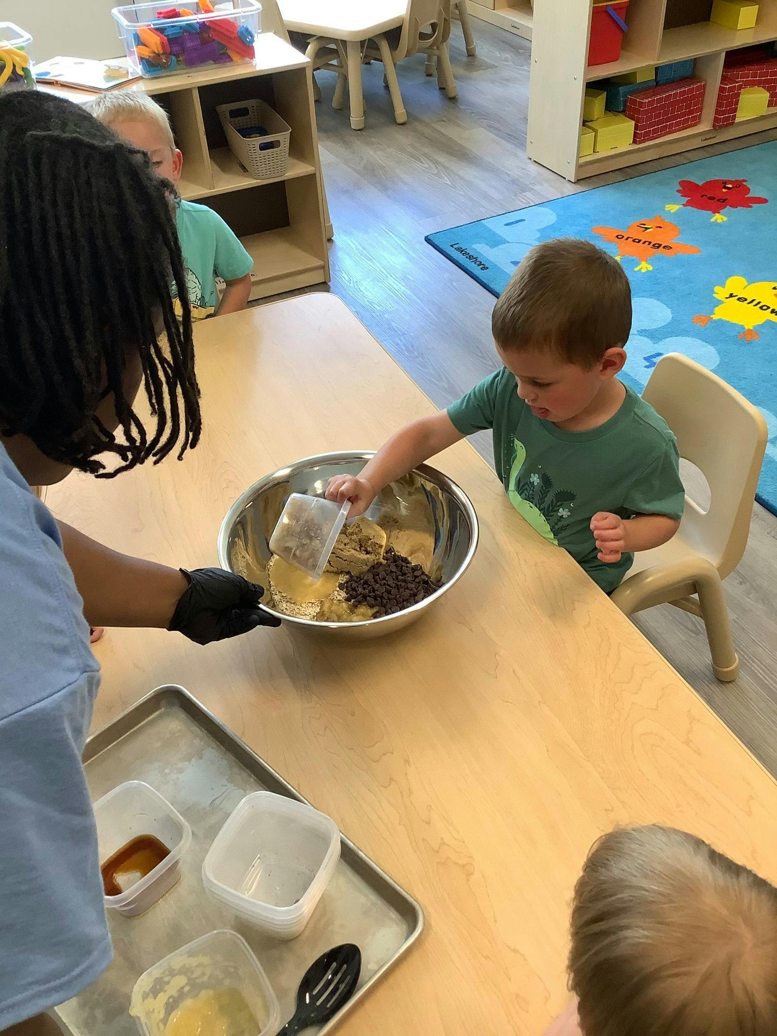 Adult and child mixing ingredients in a bowl in a classroom