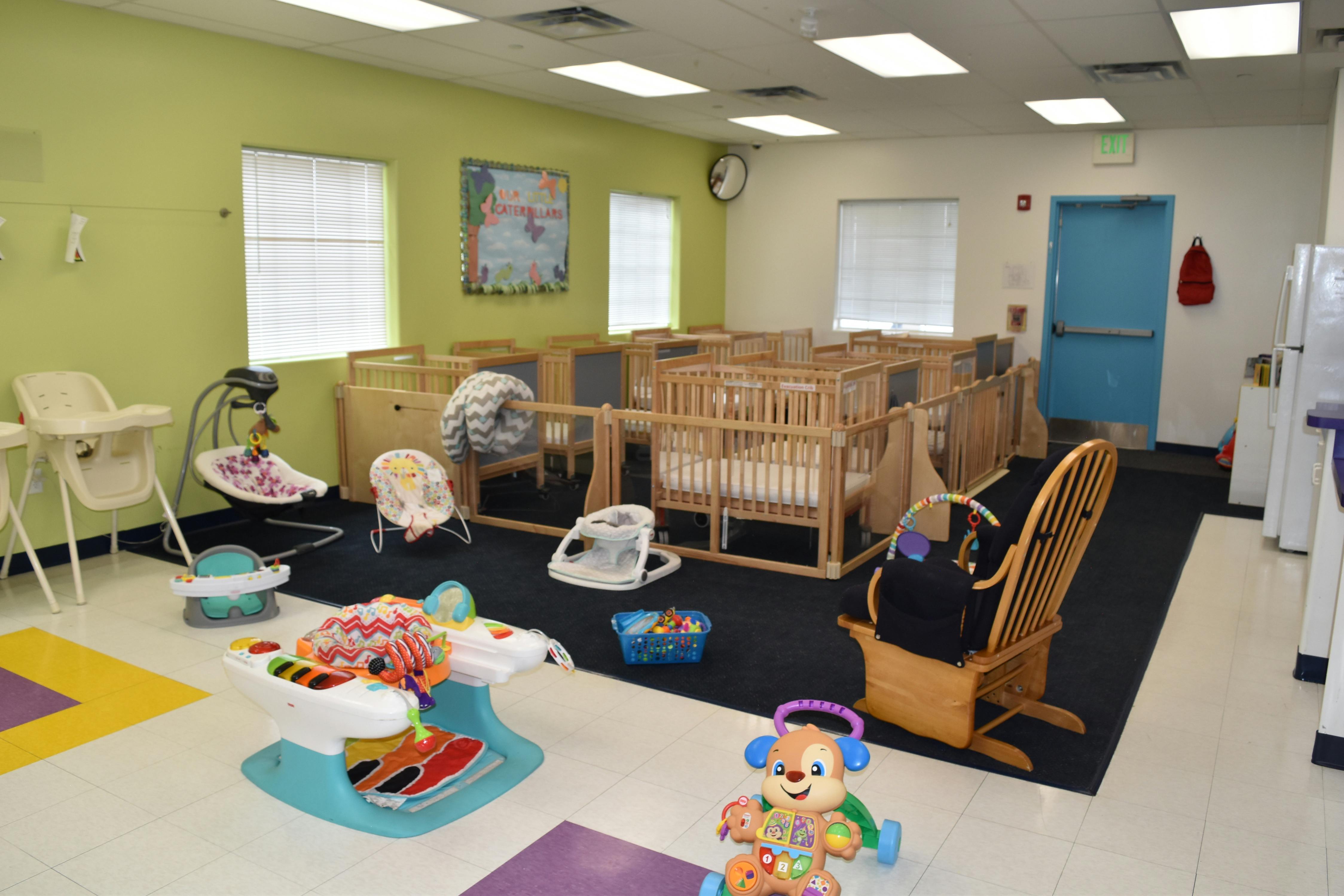 Daycare room with multiple cribs, infant swings, and play mats