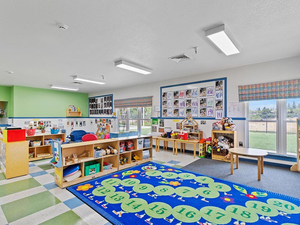 An empty children's classroom with a numerical rug