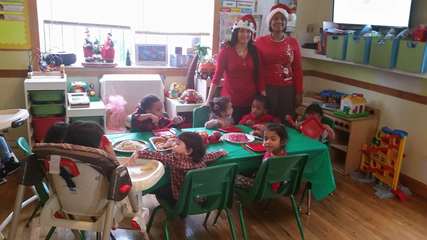 Two people in Santa hats with children at a table