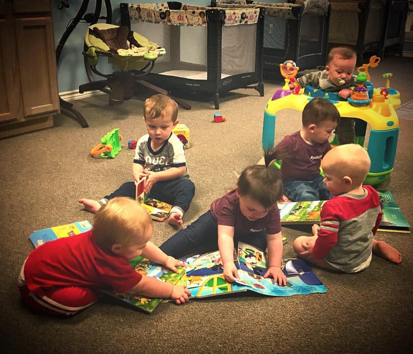 Multiple children playing with toys and books on a carpeted floor