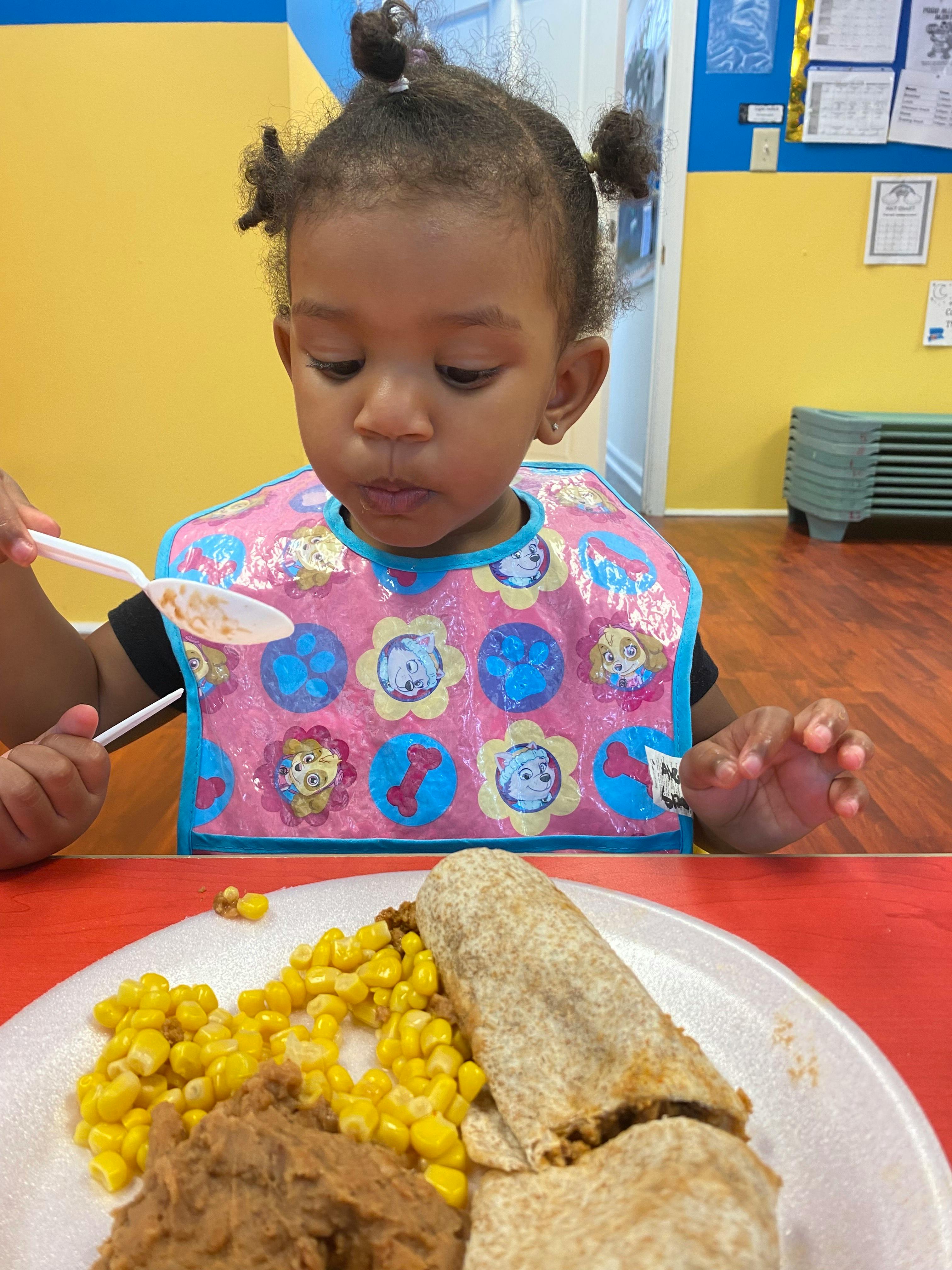 Child in a bib eating with a spoon