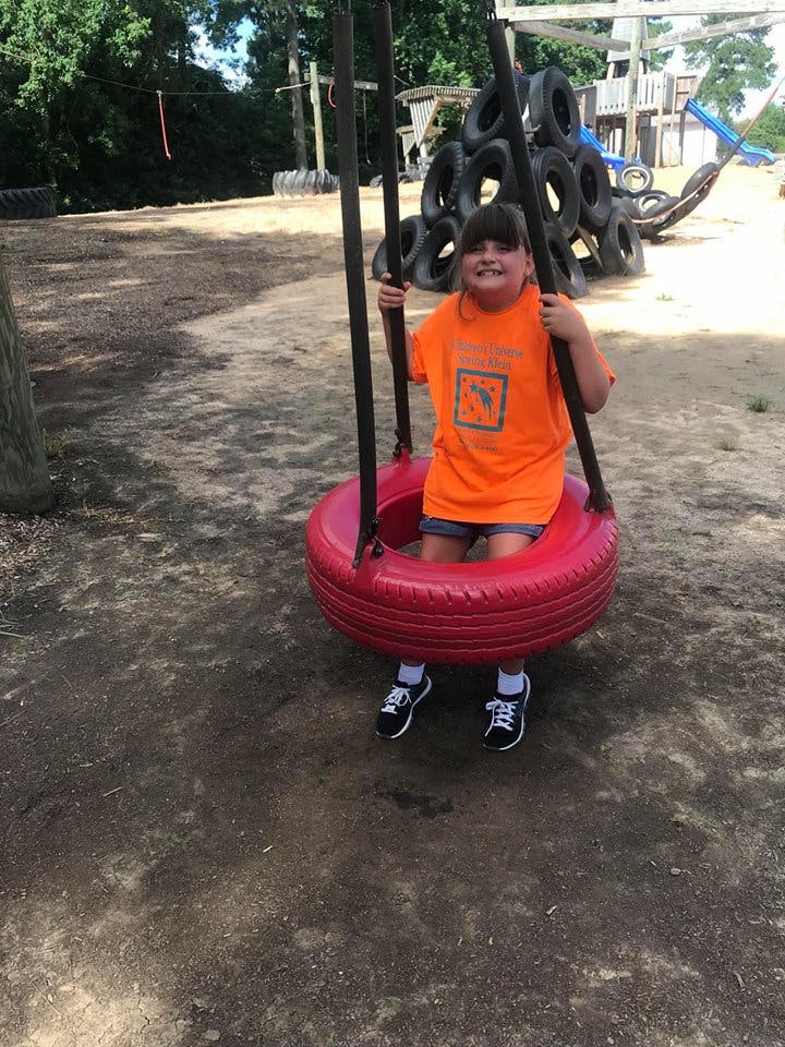 Child sitting in a red tire swing