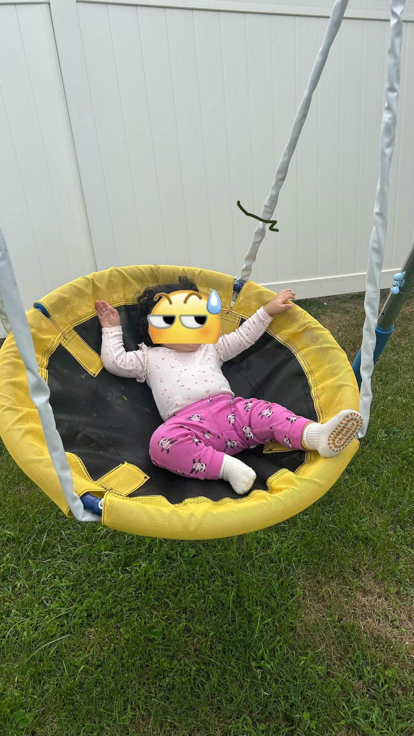 Child lying on a yellow circular saucer swing