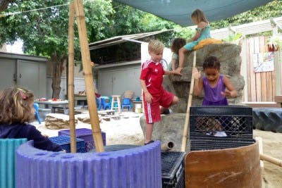 Children playing on a rock structure and in a sandbox