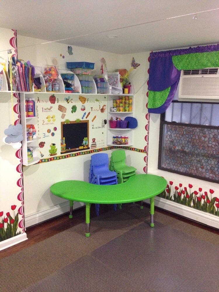 Classroom with green table, blue and green chairs, shelves, and window