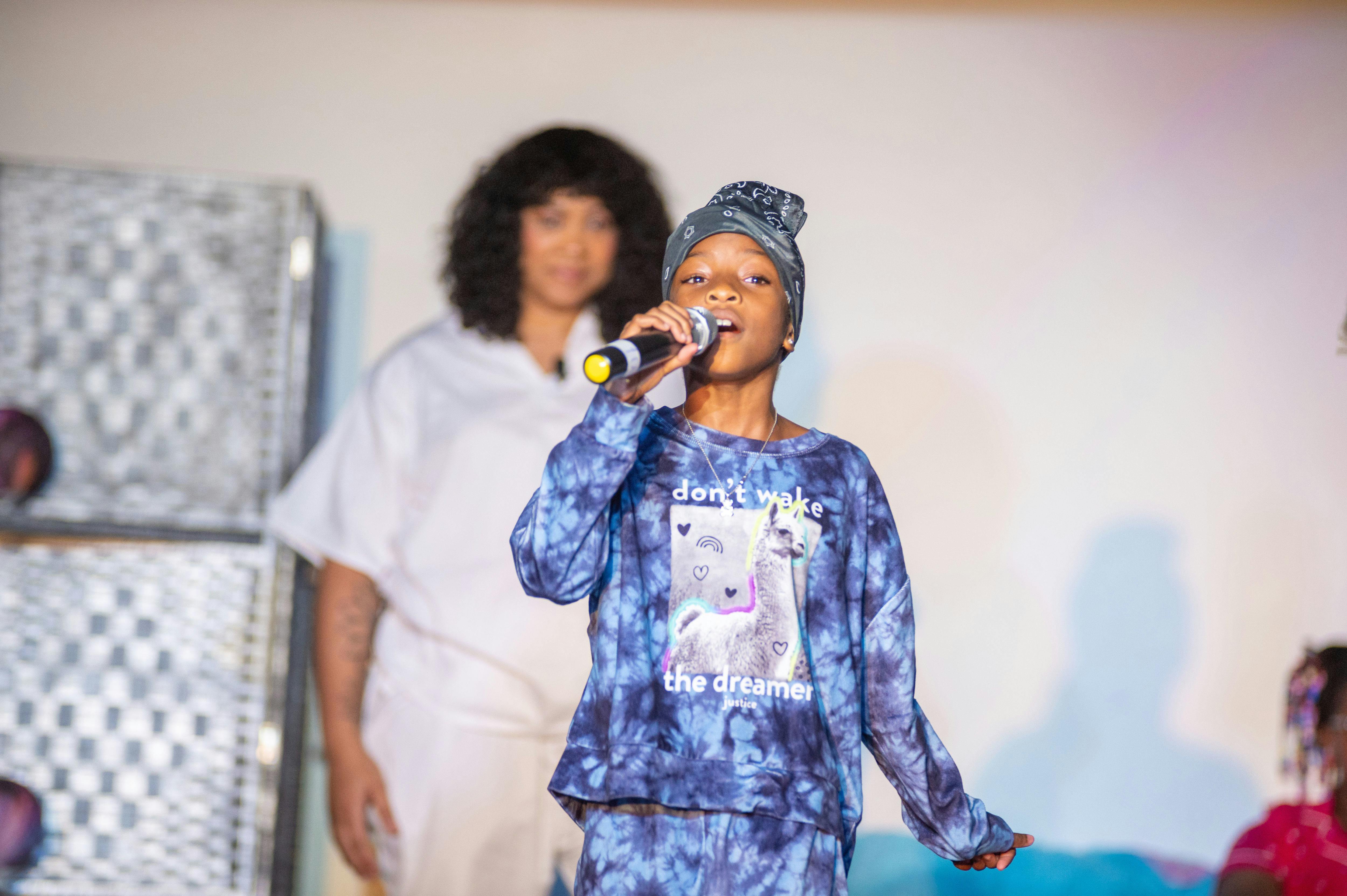 Child singing into a microphone on stage