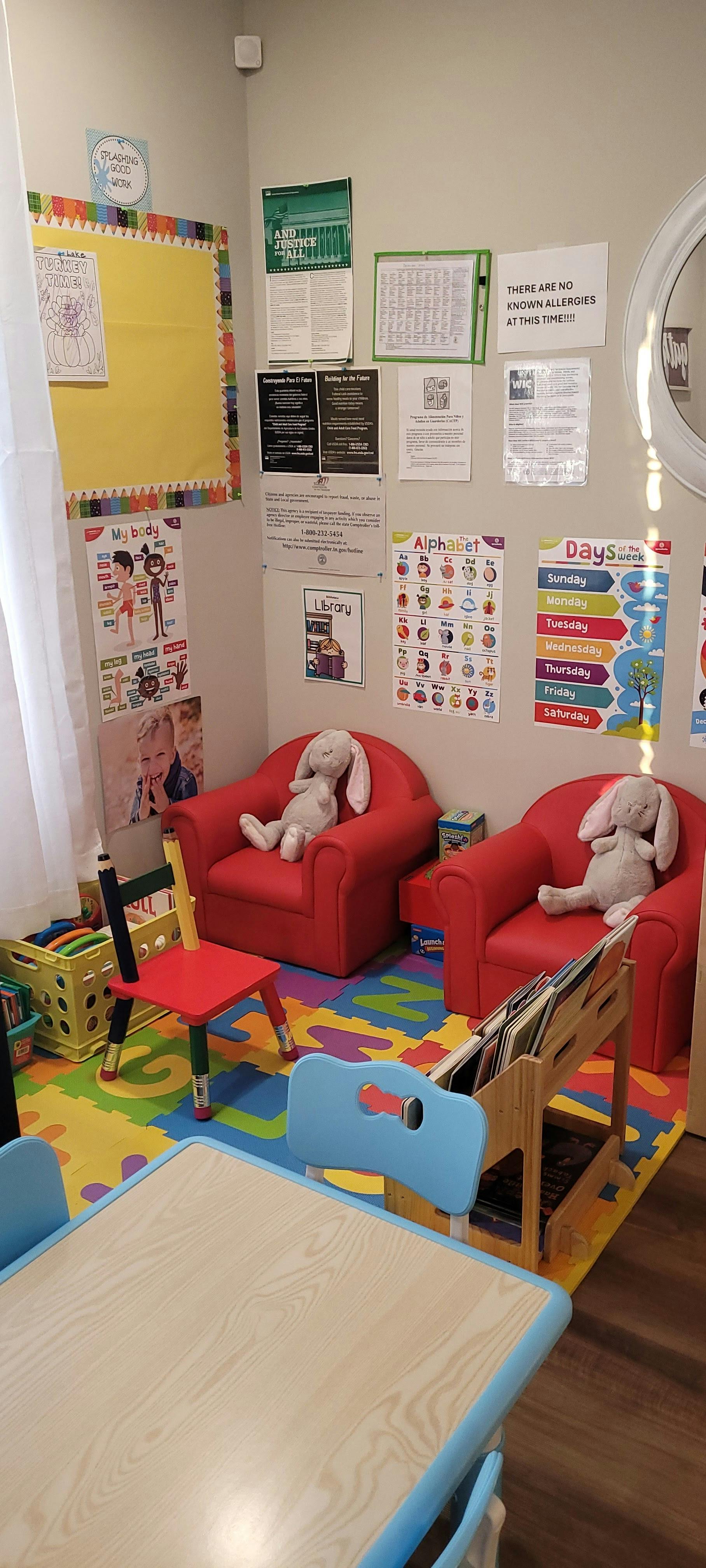Children's play area with small red chairs, a table, and colorful floor mats