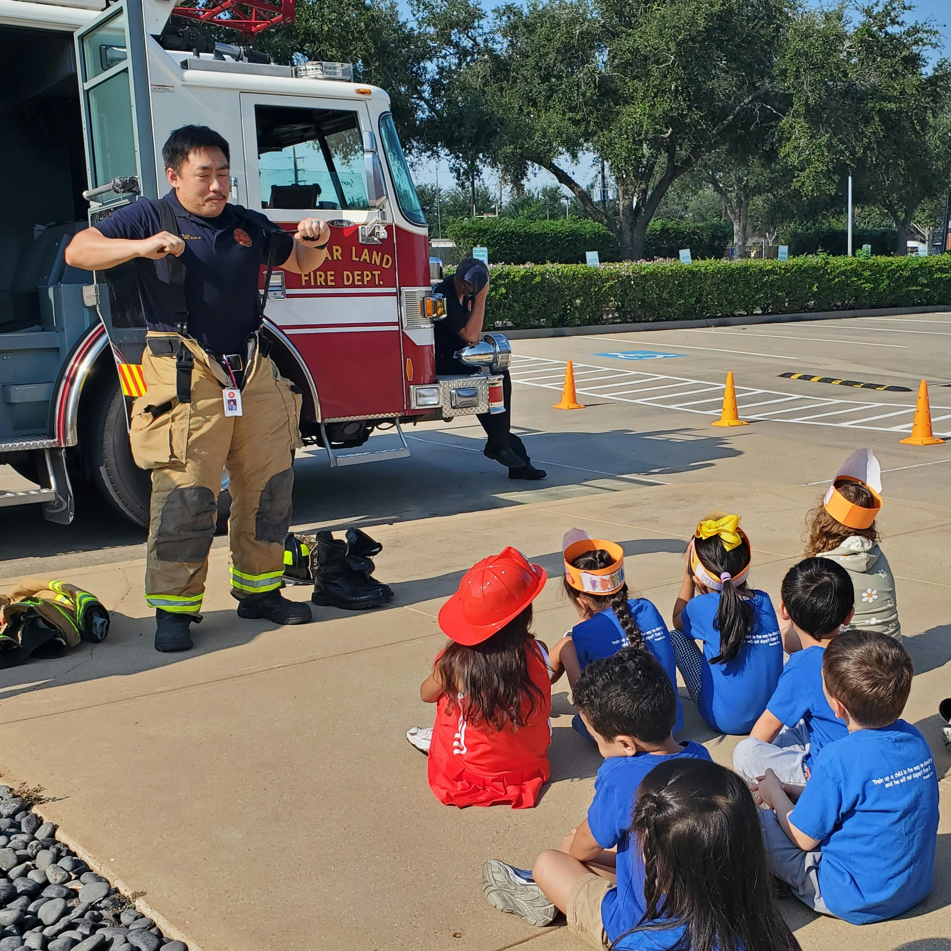 Firefighter in uniform talking to a group of children