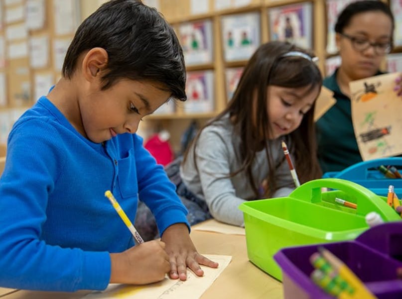 Child drawing at a table in a classroom
