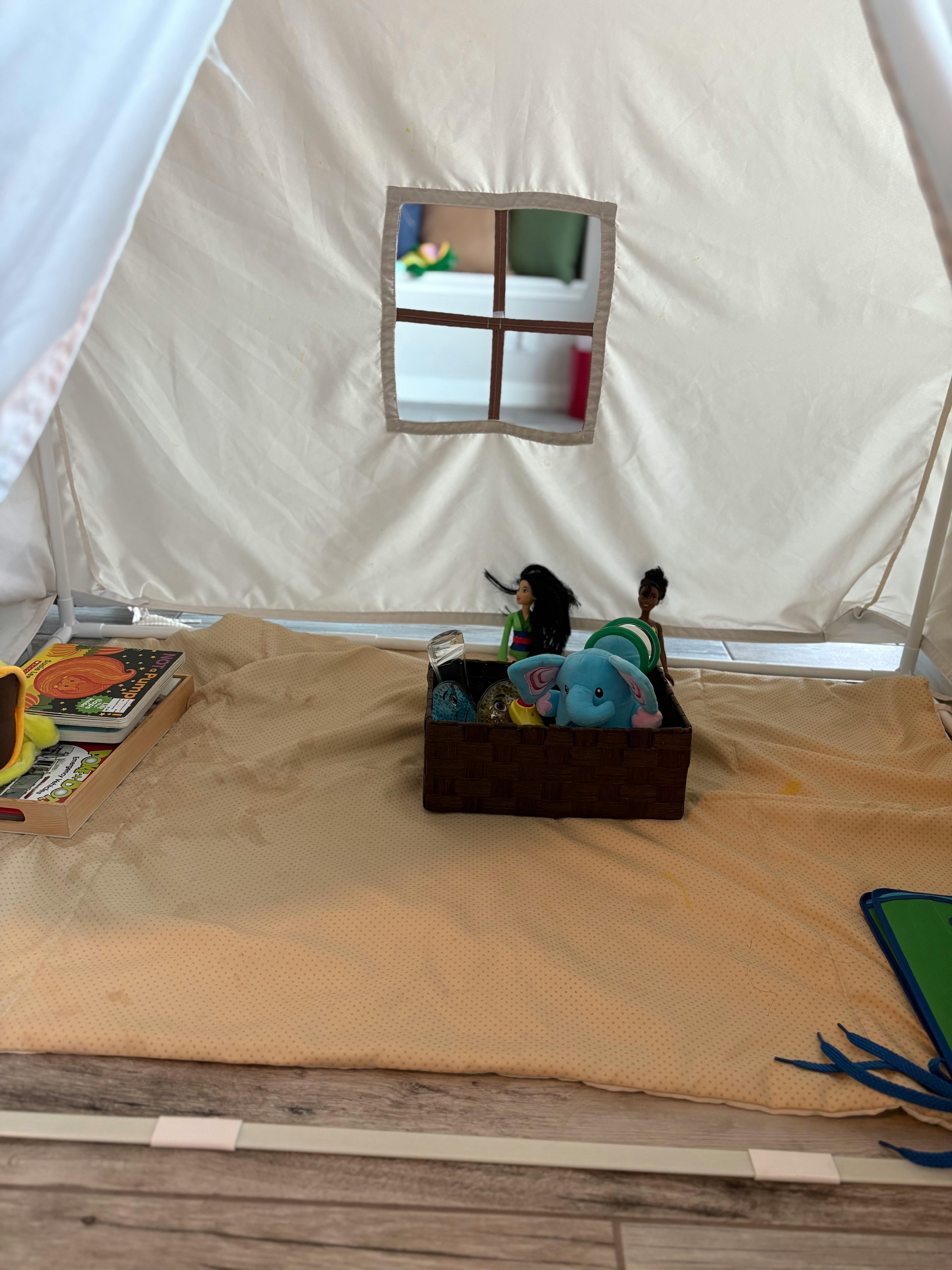 Inside a play tent with a window, books, and a box of toys