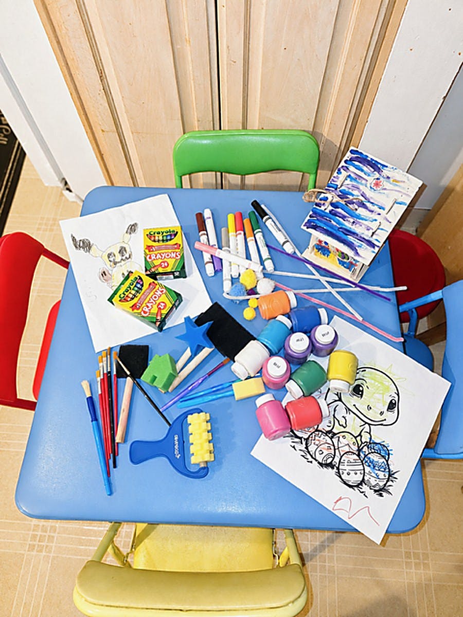 Art supplies and coloring pages on a small blue table