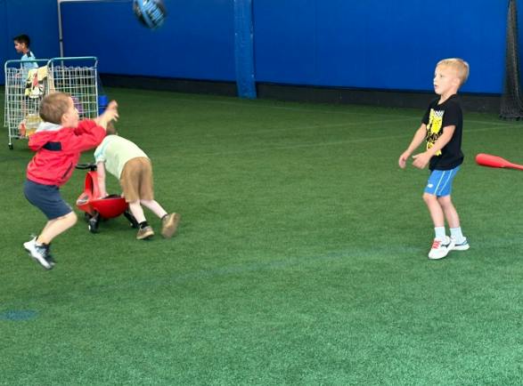 Children playing with a ball on an indoor artificial grass field