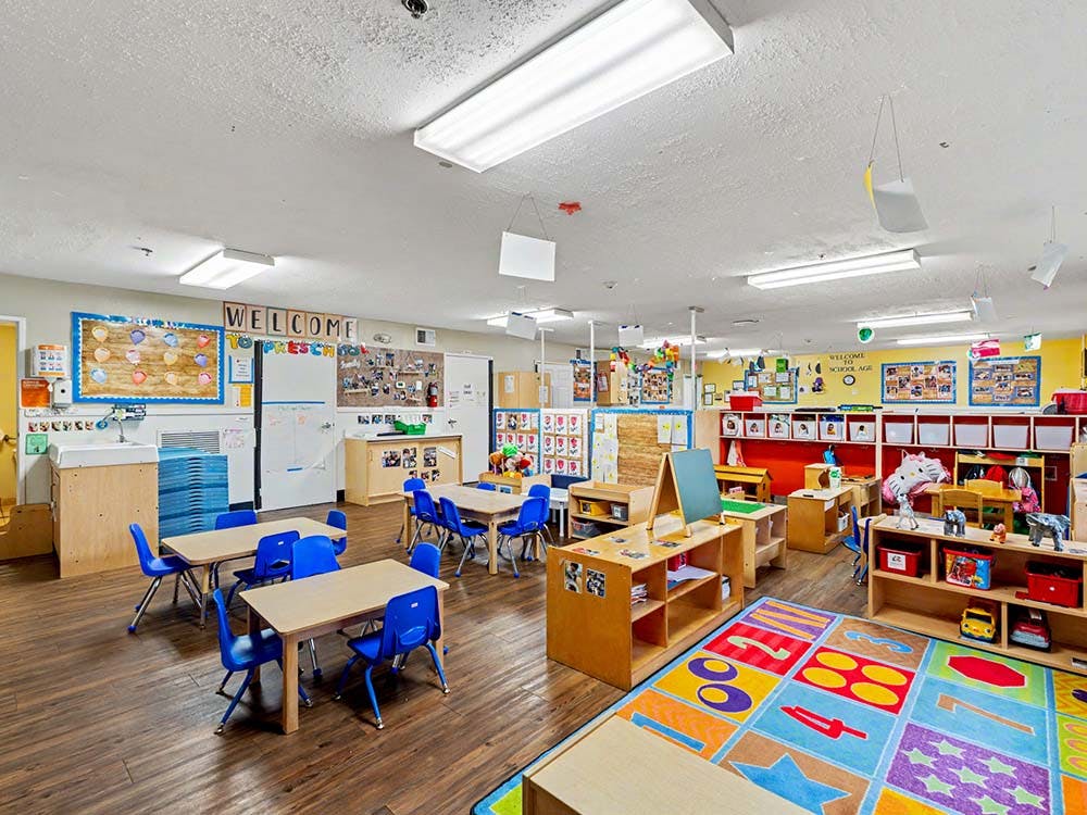 Classroom with small tables, chairs, toys, and educational decorations