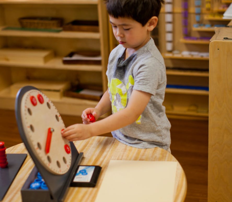 Child playing with a clock puzzle on a table