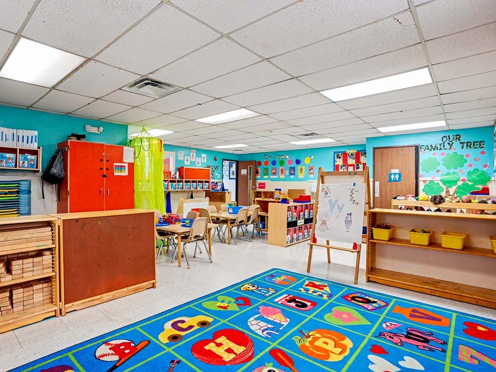 Classroom with child-sized tables and chairs, a colorful rug, and cubbies