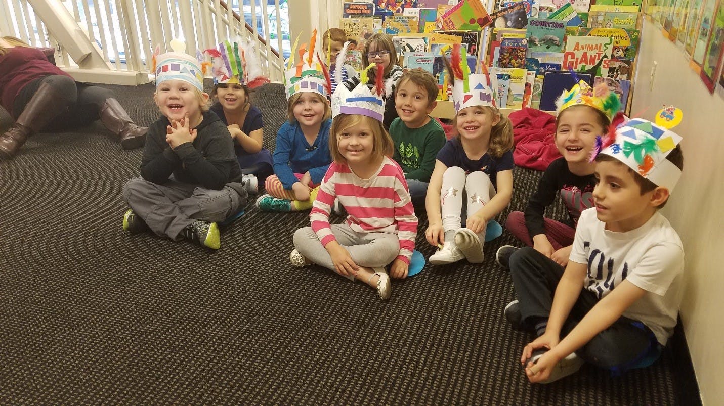 Group of children sitting on the floor wearing paper crowns